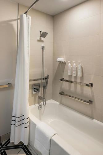 a white bathroom with a tub and a shower curtain at Oshkosh Marriott Waterfront Hotel & Convention Center in Oshkosh