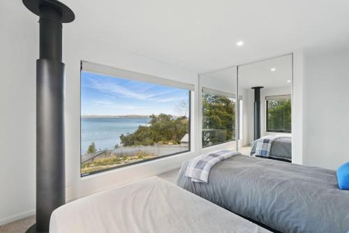 a bedroom with a large window overlooking the ocean at Modern Coastal Retreat and Hot Tub in Carlton