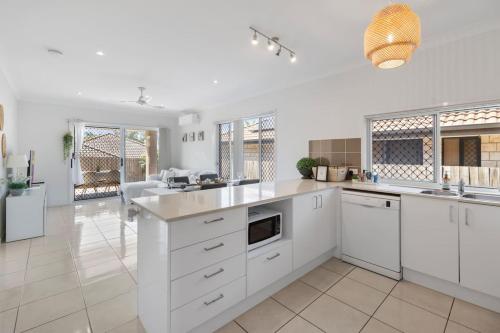 a large white kitchen with white cabinets and appliances at Modern 3BR Home in Peaceful Deebing Heights in Loamside