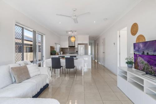 a living room with a white couch and a kitchen at Modern 3BR Home in Peaceful Deebing Heights in Loamside