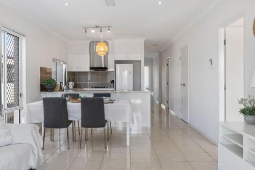 a white kitchen with a table and chairs at Modern 3BR Home in Peaceful Deebing Heights in Loamside