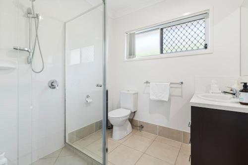 a bathroom with a shower and a toilet and a sink at Modern 3BR Home in Peaceful Deebing Heights in Loamside