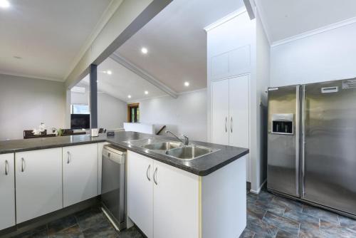 a kitchen with white cabinets and a stainless steel refrigerator at Spacious 5BR Retreat with Balcony Near Hotspots in Springwood