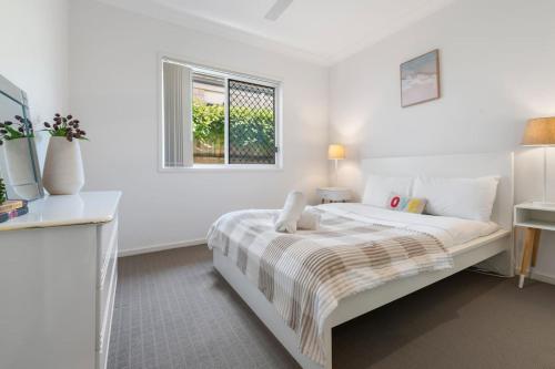 a white bedroom with a bed and a window at Modern 3BR Home in Peaceful Deebing Heights in Loamside