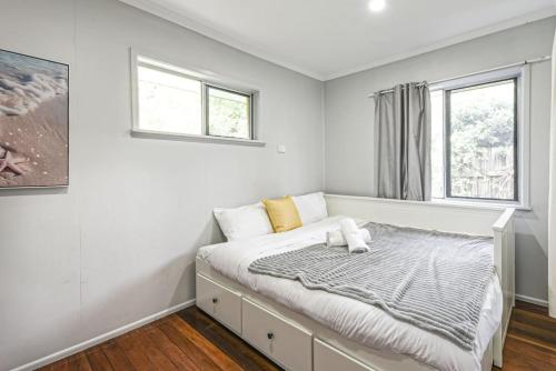 a bed in a room with two windows at Spacious 5BR Retreat with Balcony Near Hotspots in Springwood