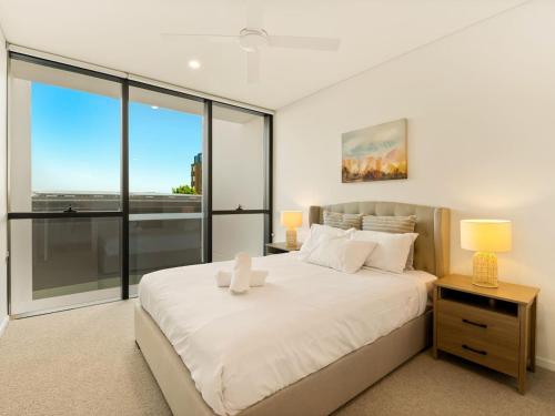 a bedroom with a large white bed and large windows at 2BR West End Apt with Parking Walk to Convention Ctr in Brisbane