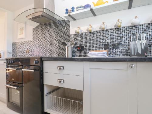 a kitchen with white cabinets and a black counter top at Rock Pool House in Helston