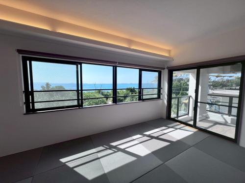 a room with windows and a view of the ocean at LAGUNA OKINAWA Beachfront YAKA in Kin