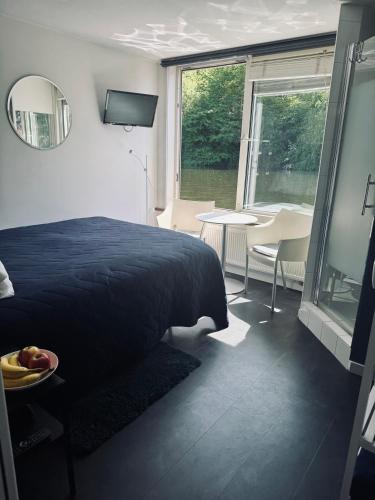 a bedroom with a bed and a table and a window at Peaceful room on a houseboat in the city centre in Amsterdam