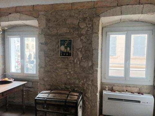 - une cuisine avec deux fenêtres et un mur en pierre dans l'établissement Charmant studio Vieux Port, à Marseille