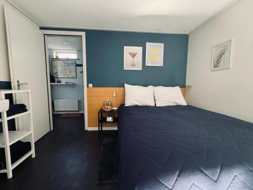 a bedroom with a bed and a blue wall at Peaceful room on a houseboat in the city centre in Amsterdam