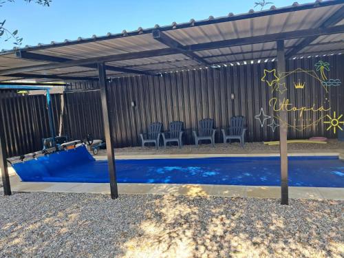 a pergola with chairs and a swimming pool at Utopía Hogar in Balneario Argentino