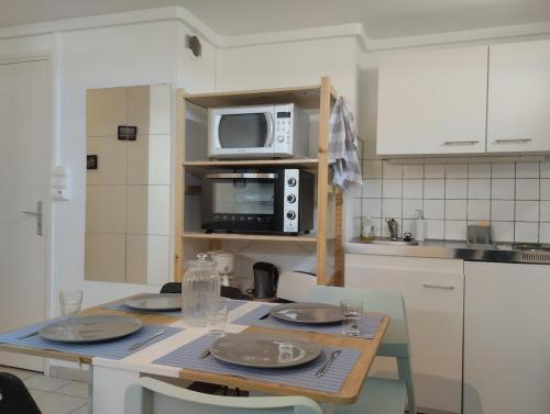 - une cuisine avec une table et un four micro-ondes dans l'établissement De l'ancre à la criée hyper centre Dunkerque, à Dunkerque