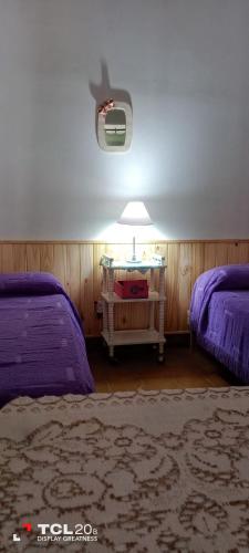 a bedroom with two beds and a table with a lamp at Hospedaje LA LUCIA in Almafuerte