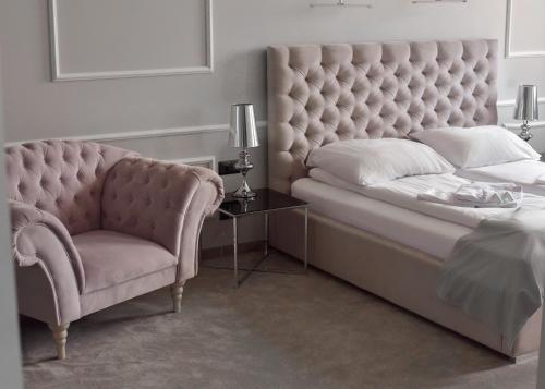 a bedroom with a large bed and a chair at Apartamenty Atmosfera Bytów in Bytów