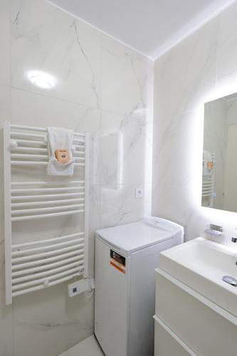 La salle de bains blanche est pourvue d'un lavabo et d'un réfrigérateur blanc. dans l'établissement Baies de Juan - Apt 4 Pers - Pool - Air Conditioning, à Antibes