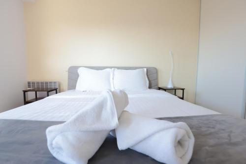 un lit avec des draps blancs et des serviettes dessus dans l'établissement Baies de Juan - Apt 4 Pers - Pool - Air Conditioning, à Antibes