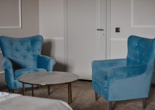 two blue chairs and a table in a room at Apartamenty Atmosfera Bytów in Bytów