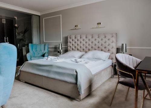a bedroom with a large bed and two blue chairs at Apartamenty Atmosfera Bytów in Bytów