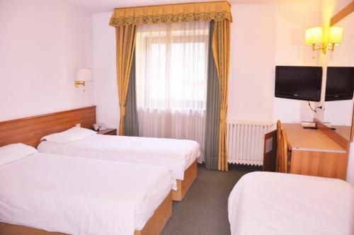 a hotel room with two beds and a television at Liberty Hotel Malé in Malè