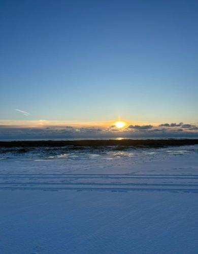 a sunset over a snowy field with the sun in the sky at Meerblick Cafe Reiten Spielplätze Animation WLAN in Fanø