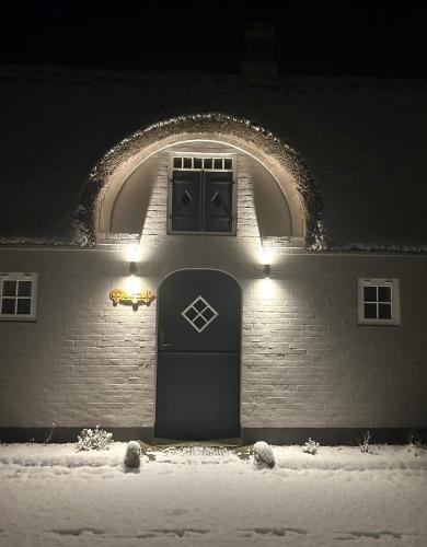 a building with a door in the snow at night at Meerblick Cafe Reiten Spielplätze Animation WLAN in Fanø