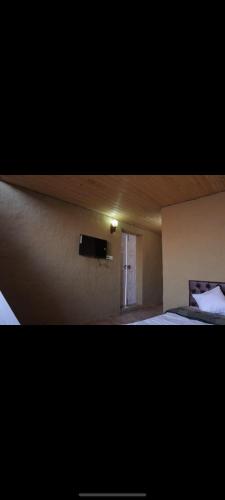 a room with a bed and a television on a wall at Rivva mud cottage in Kūfrī