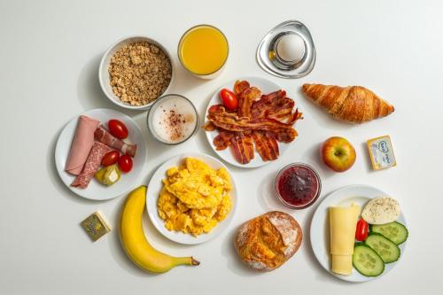 a white table topped with plates of breakfast foods at Hotel Gute Hoffnung Pforzheim in Pforzheim