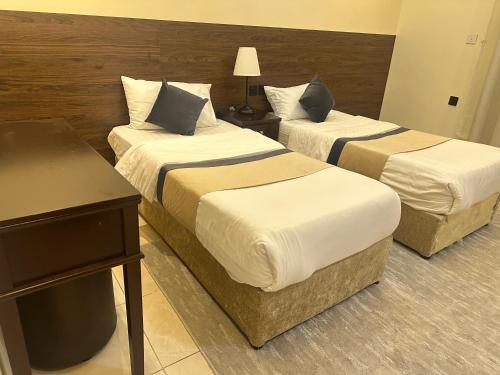 a hotel room with two beds and a desk at خيال الفارس للشقق المخدومة in Quwayzah