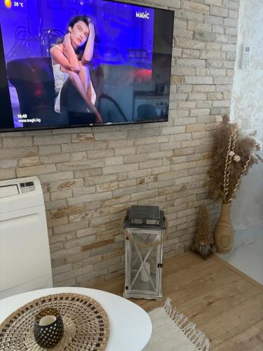 a living room with a tv on a brick wall at Boutique apartment Bansko Bell Tower in Bansko
