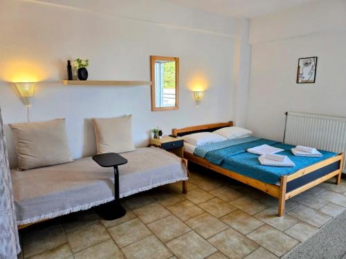 a bedroom with two beds and a table and a window at Philoxenia Beach Apartments Stavros in Stavros