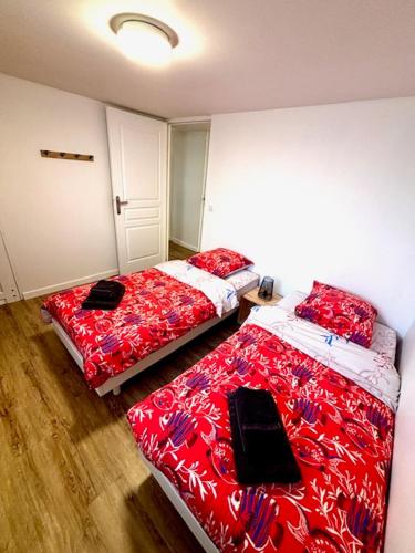 - 2 lits dans une chambre avec des draps rouges et blancs dans l'établissement Duplex, terrasse, vue mer, 30m plage, à Port-Bail-sur-Mer