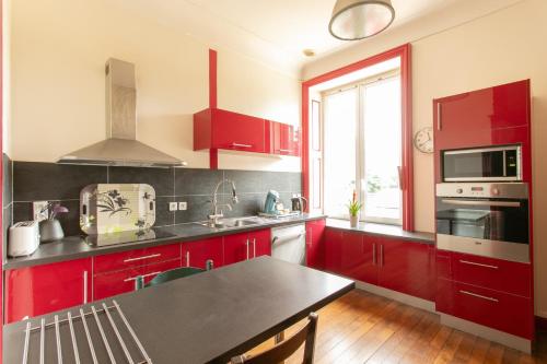a kitchen with red cabinets and a table in it at CHATEAU du PERRAY in Saint-Mars-du-Désert