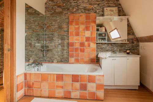 a bathroom with a tub and a stone wall at CHATEAU du PERRAY in Saint-Mars-du-Désert
