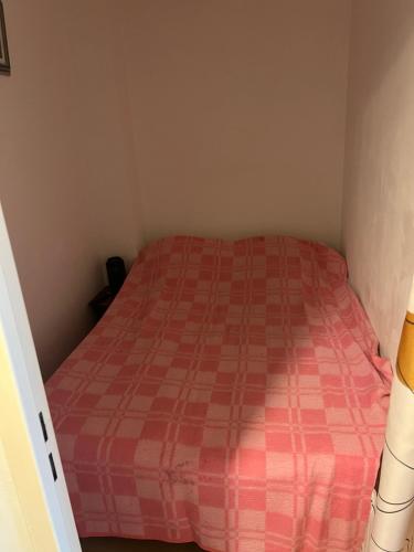 une petite chambre avec un lit avec un couvre-lit à carreaux rouges dans l'établissement Studio cabine près de la plage, au Lavandou