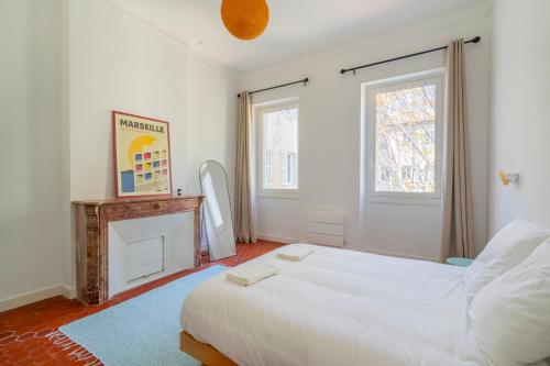 - une chambre avec un lit blanc et une cheminée dans l'établissement Le Palais Longchamp, appart lumineux emplacement idéal, à Marseille