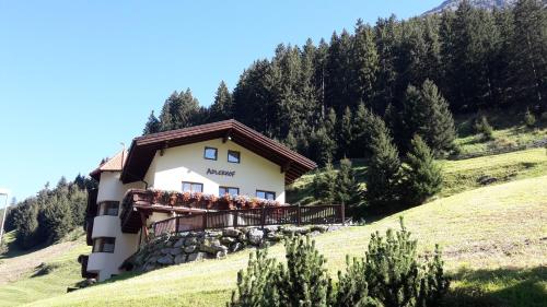 a building on a hill with people on a balcony at Adlerhof in Sankt Leonhard im Pitztal