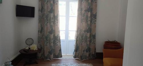 a room with a window with curtains and a chair at António Augusto Apartment in Coimbra