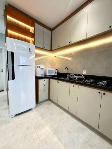 a kitchen with white cabinets and a white refrigerator at Flats Luxo - Apartamentos 2 Quartos com Garagem in Palmas