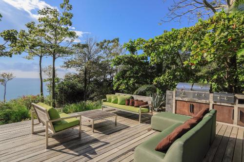 a patio with couches and chairs on a wooden deck at Entre Lomas Boutique in Montezuma