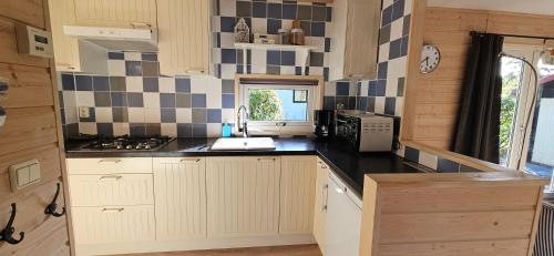 a kitchen with white cabinets and a black counter top at De Kleine Kriemelkuil - Het Vosje in Ermelo