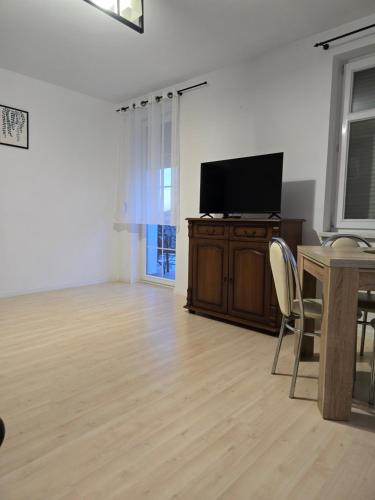 a living room with a flat screen tv and a wooden table at Apartament Z widokiem na Czos Mrągowo in Mrągowo