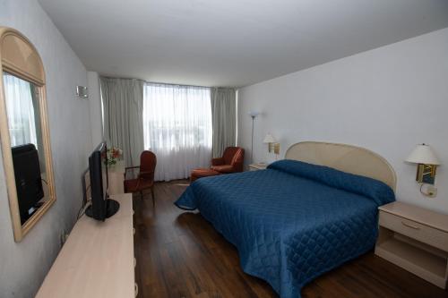 a bedroom with a blue bed and a television at Hotel San Francisco in Toluca