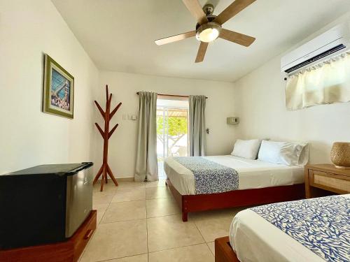 a bedroom with two beds and a flat screen tv at Hotel Carey Beach Baru in Baru