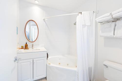 a white bathroom with a tub and a sink and a mirror at 2 Coastal Studios at Cayucus Beach Access Ocean Views in Cayucos