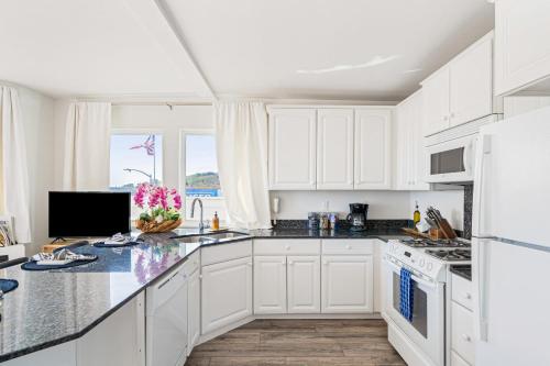 a kitchen with white cabinets and a counter top at 2 Coastal Studios at Cayucus Beach Access Ocean Views in Cayucos