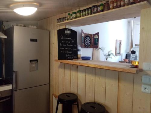 La cuisine est équipée d'un réfrigérateur et d'un comptoir avec tabourets. dans l'établissement La cabane 1949, à Gujan-Mestras