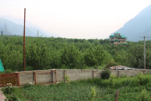 a brick wall in a field with a house in the background at Flugafen B&B- A Peaceful home in Apple Orchards in Manāli