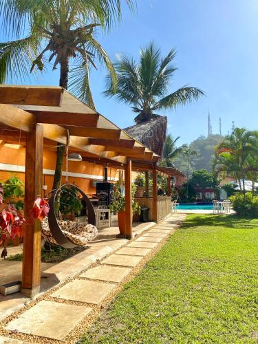 a resort with a wooden pavilion and a pool at Pousada Dolce Vita in Itanhaém