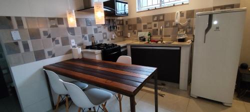 a kitchen with a wooden table and chairs and a refrigerator at Apartmento com Jacuzzi para DOIS Bingen Petrópolis in Petrópolis